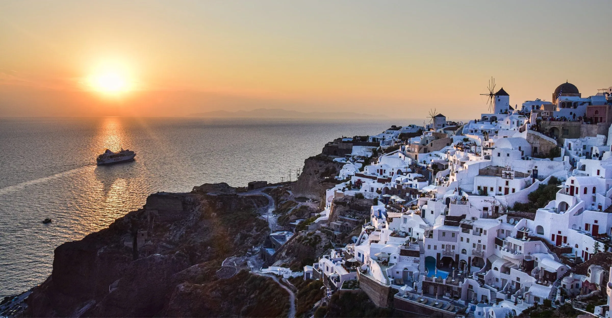 Sunset over the caldera at Oia, Santorini, with a ship on the Aegean