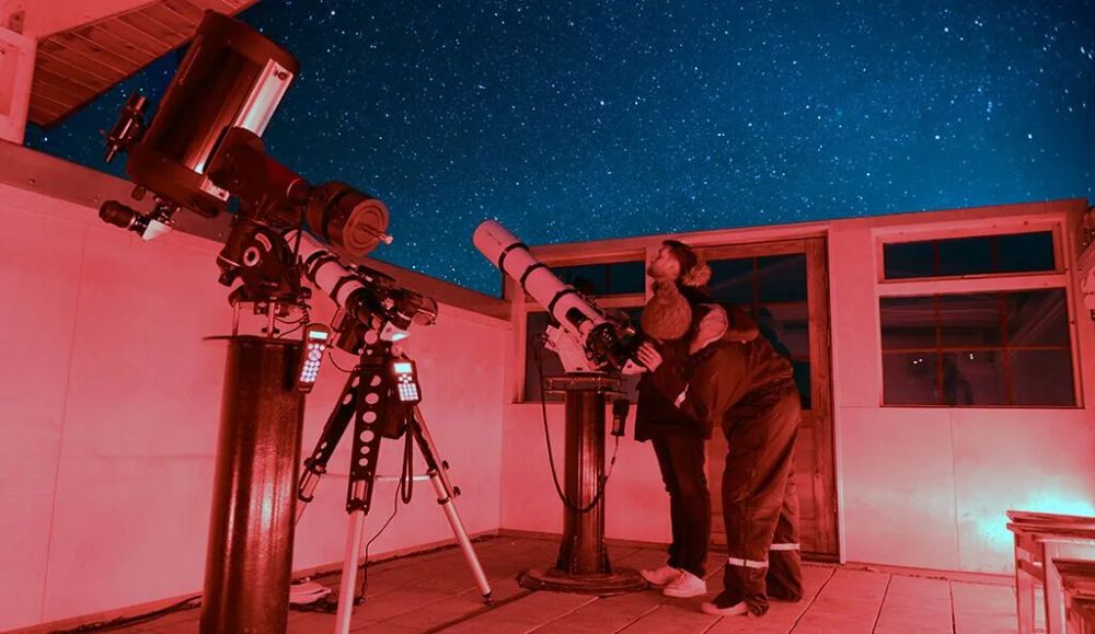 Guests at the telescopes in the hotel observatory under a starry sky