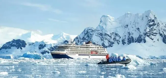 A Hapag-Lloyd expedition ship in Antarctica, with guests in a Zodiac