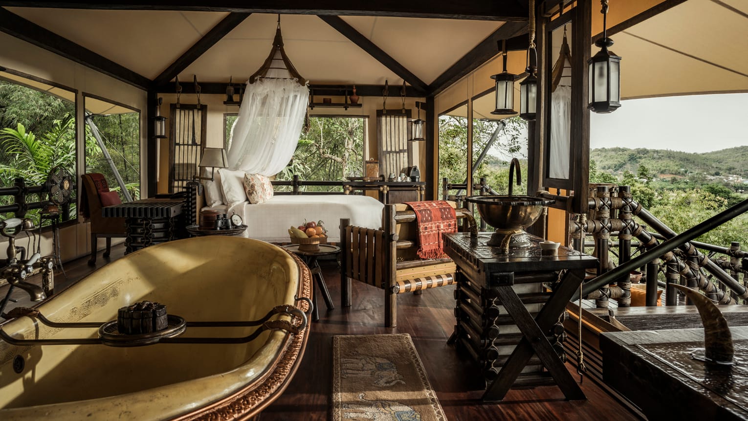 A Bill Bensley tent with a copper bathtub, teak furniture and a mosquito-netted bed