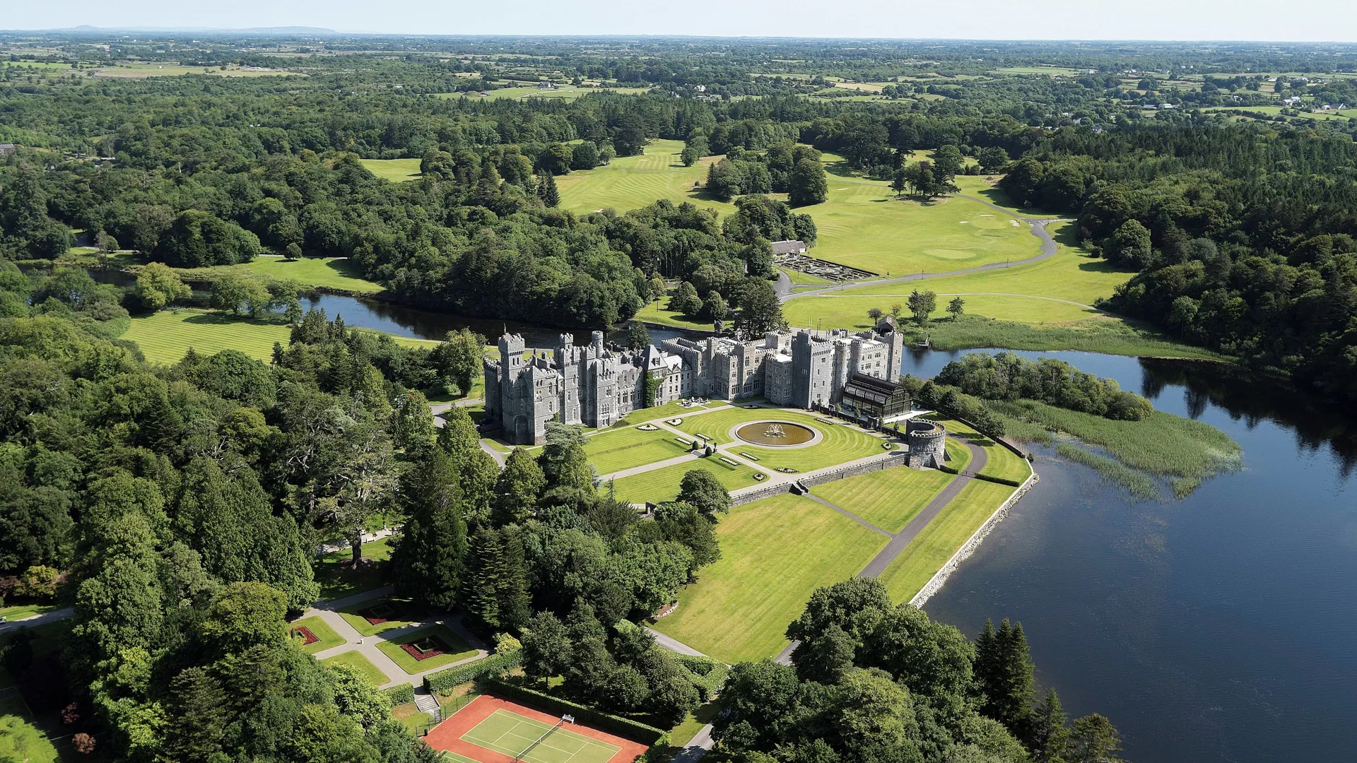 Aerial view of Ashford Castle beside the lake, surrounded by woodland and lawns