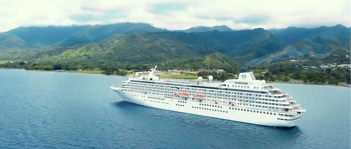 A Crystal ship at anchor off a lush, mountainous island