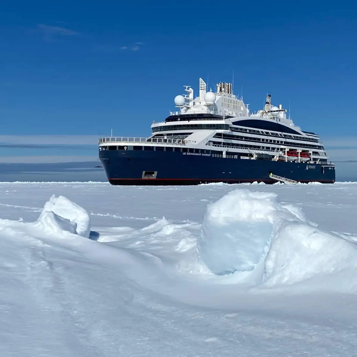 Le Commandant Charcot moored in polar sea ice under a clear blue sky