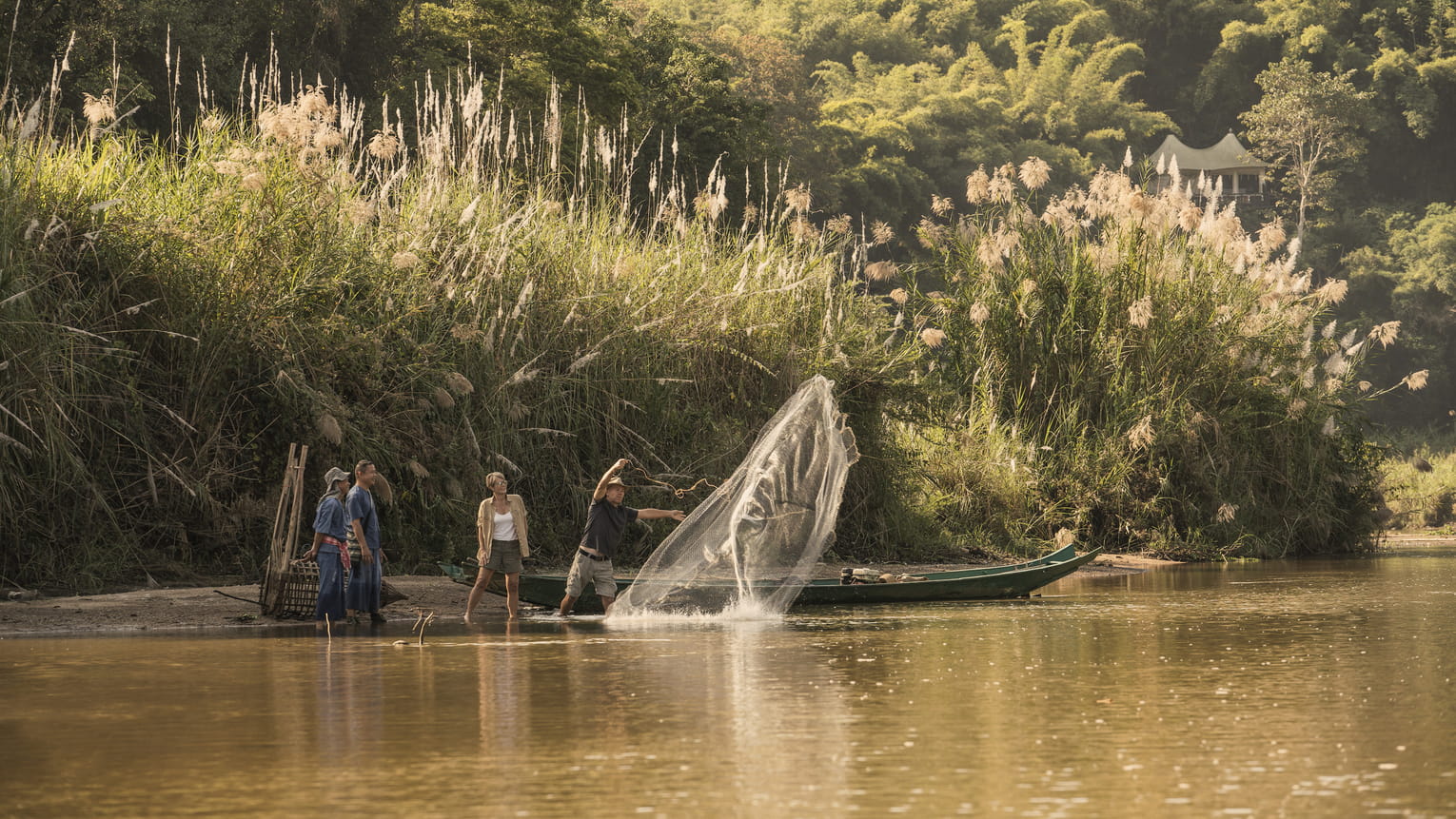 A local fisherman casting a net from the bank of the Ruak River