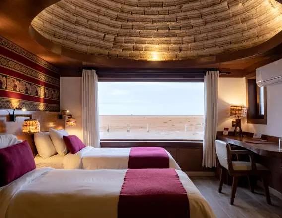 A room beneath a domed salt-block ceiling, with a wide window onto the Salar