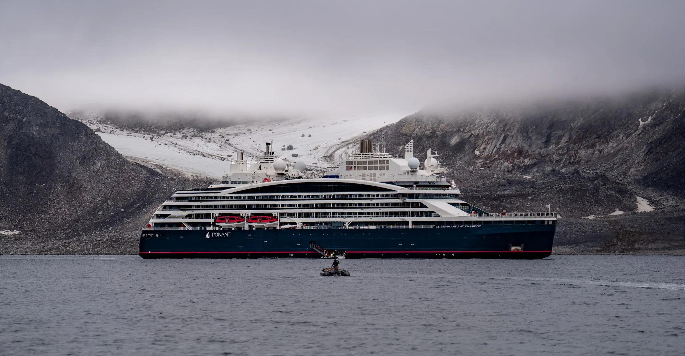 Ponant's Le Commandant Charcot at anchor in an Arctic fjord, with a Zodiac alongside