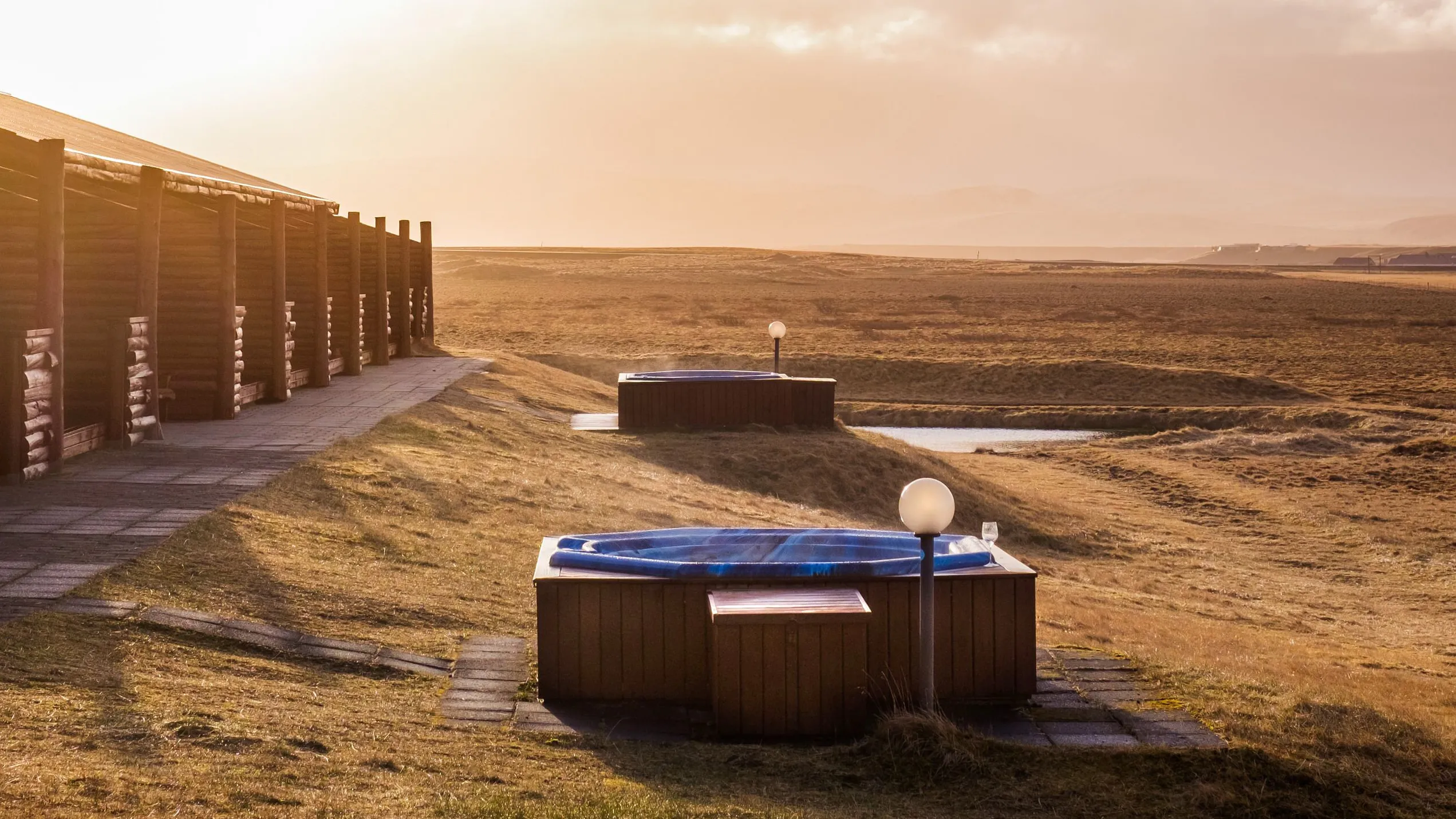 Outdoor hot tubs beside the hotel, looking across open countryside at sunset