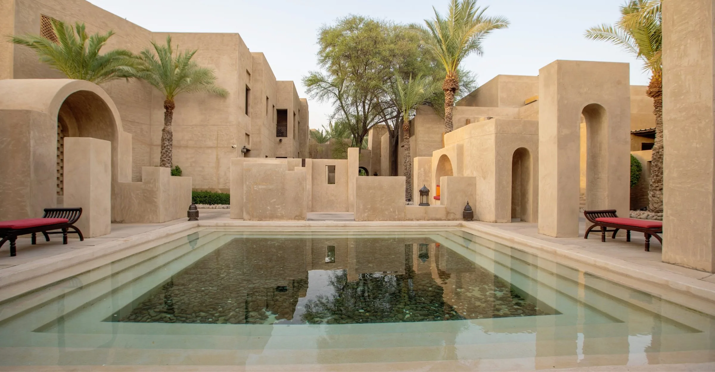 A reflecting pool among sand-coloured courtyards and palms at a desert resort