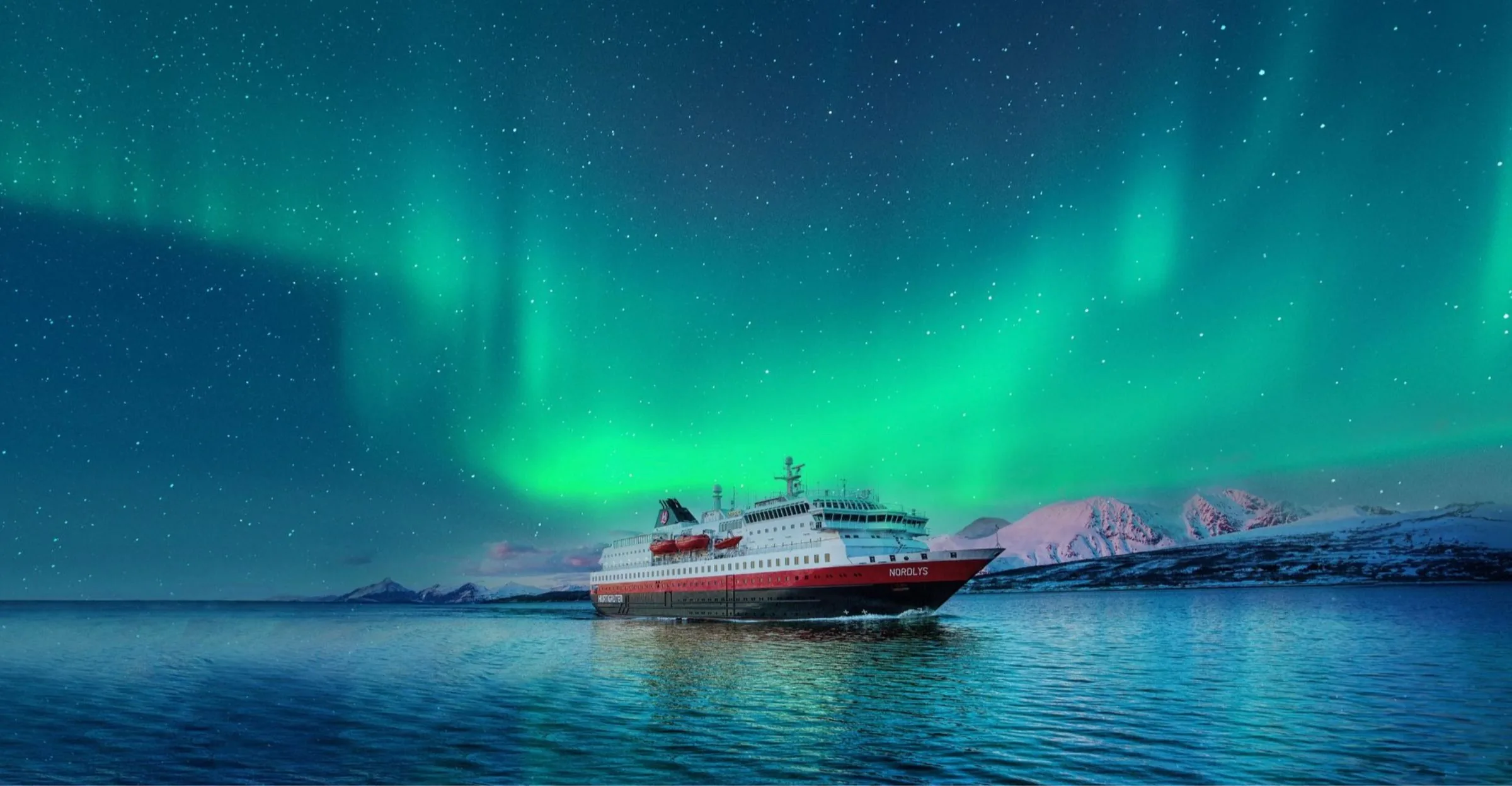 Hurtigruten's MS Nordlys sailing beneath the Northern Lights past snow-capped Norwegian peaks